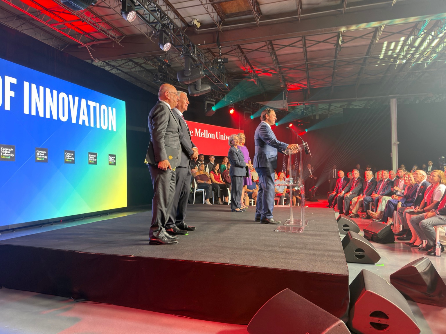 Wide view of the CMU Miami launch stage, university screens and seated audience at Soho Studios